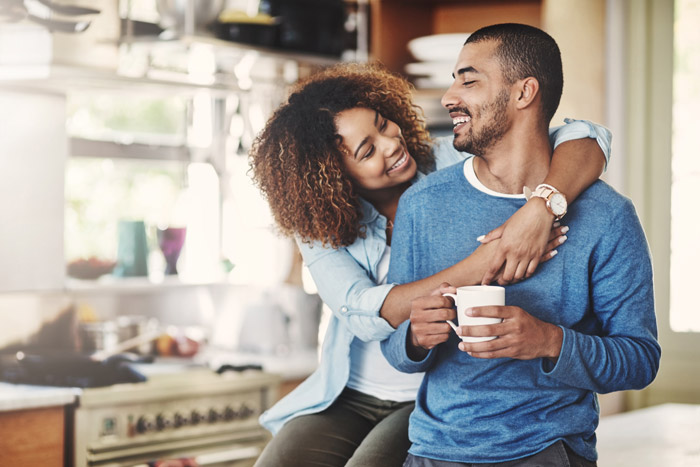 mixed-race couple in the kitchen smiling and embracing each other