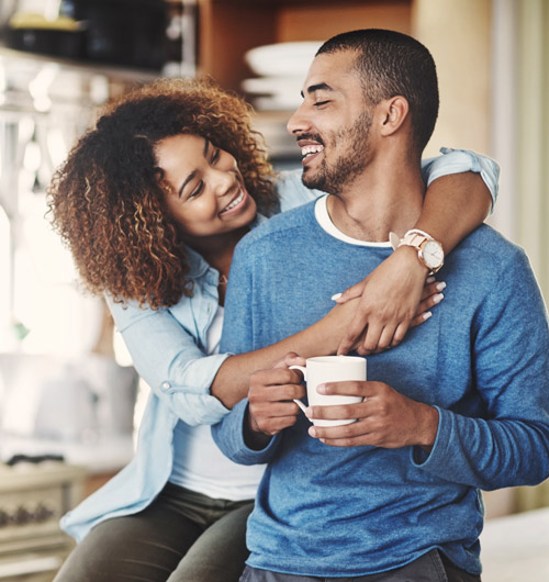mixed-race couple in the kitchen smiling and embracing each other